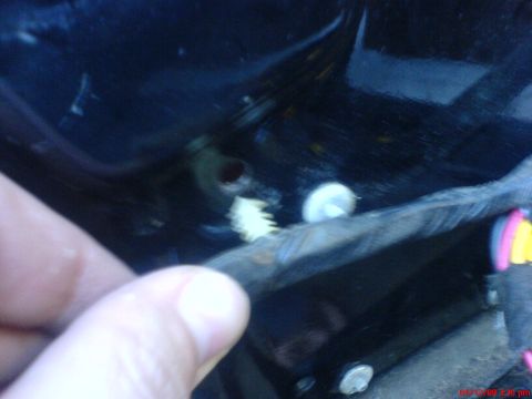 1986 Ford Bronco - A hand is visible in the foreground, pointing to a white plastic clip inside a dark car door panel. Wiring is also visible.