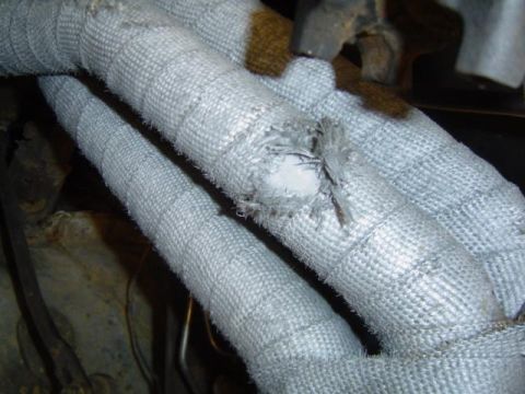 1979 Ford Bronco - Close-up of damaged exhaust pipe heat wrap with visible fraying and insulation.