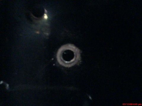1986 Ford Bronco - A close-up shot of a dark surface with a hole, possibly a part of a vehicle. The Supermotors.net logo is visible in the corner.