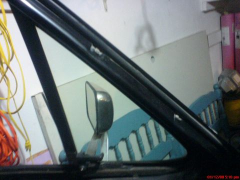 1986 Ford Bronco - Close-up view of the interior of a vehicle, focusing on the side mirror and window frame.