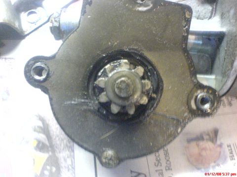 1986 Ford Bronco - Close-up of a starter motor's gear and housing, with visible text from a superimposed document.