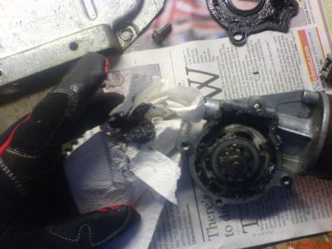 1986 Ford Bronco - Disassembled automotive part covered in grease and debris, resting on a newspaper.