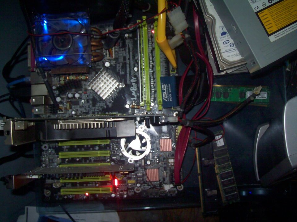 Computer motherboard with blue fan, RAM sticks, graphics card, hard drive, and CD-ROM drive