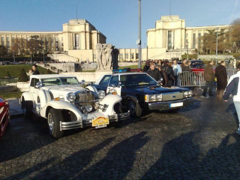 1991 Ford Crown Victoria - Two vintage cars, one white and one a police car, are parked outside a grand building.