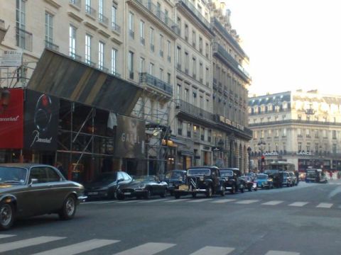 1991 Ford Crown Victoria - A street in Paris shows a row of classic cars parked in front of buildings, with one building undergoing renovation.