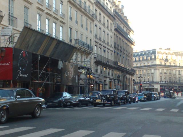 Paris street with Baccarat store under construction, row of vintage cars parked along the curb