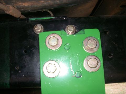 1978 Ford Bronco - Close-up of a green bracket attached to a black frame with multiple bolts.