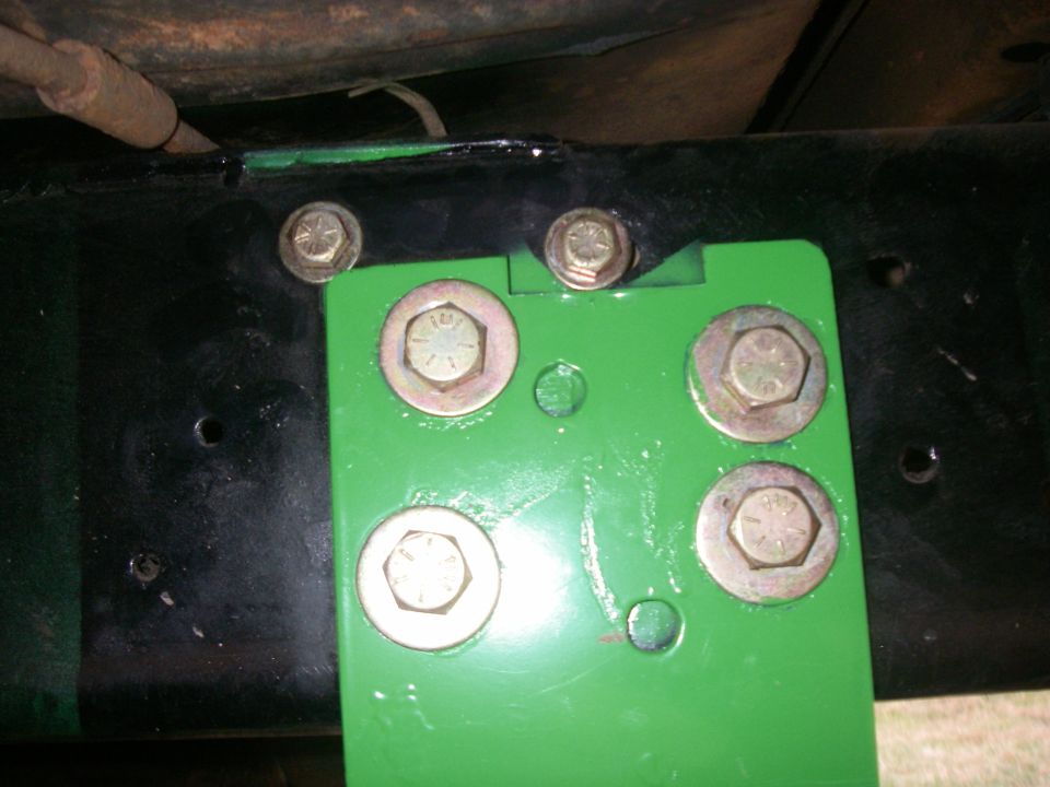 Green metal bracket bolted to black frame with hex bolts