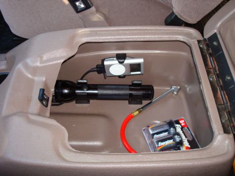 1992 Ford Bronco - Interior view of a vehicle's center console storage compartment containing various items.