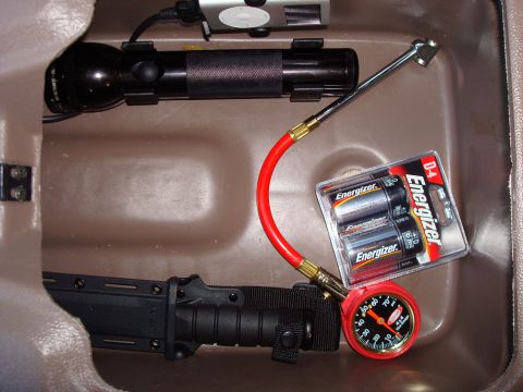 1992 Ford Bronco - A storage compartment holds a flashlight, Energizer batteries, a tire pressure gauge, and a knife.