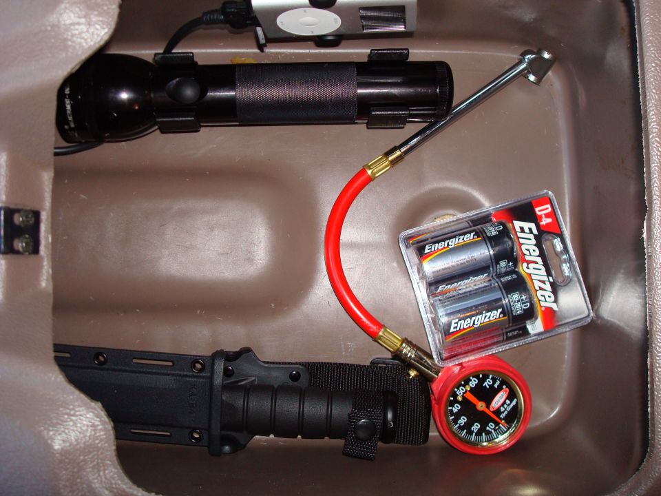 Interior storage compartment with flashlight, tire gauge, batteries, and knife