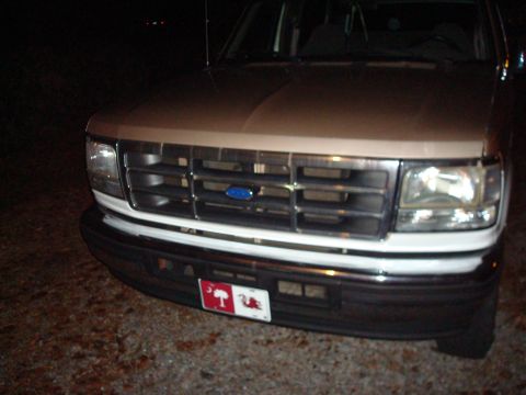 1992 Ford Bronco - Front view of a 1992 Ford Bronco with a tan hood and white grille, parked at night.
