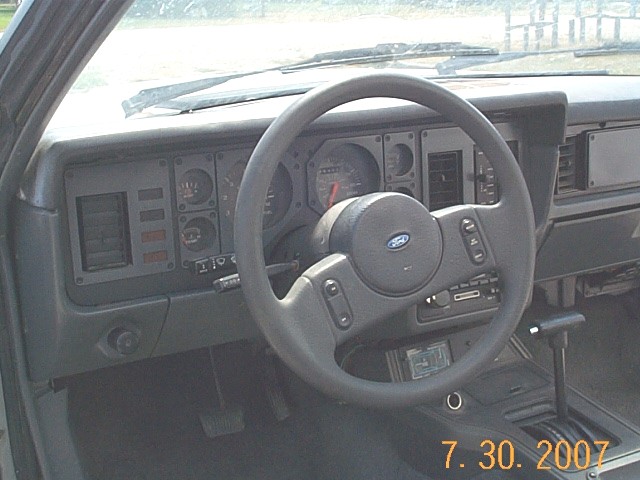 Gray Fox-body Ford Mustang interior with Ford steering wheel, gauge cluster, and automatic shifter