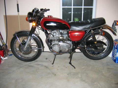 1985 Ford LTD Crown Victoria - A vintage Honda motorcycle with a two-tone red and black fuel tank is parked on a concrete floor.