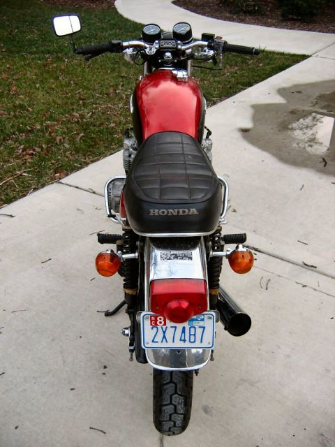 1985 Ford LTD Crown Victoria - The rear of a classic Honda motorcycle is shown, with its red fuel tank and black seat clearly visible.