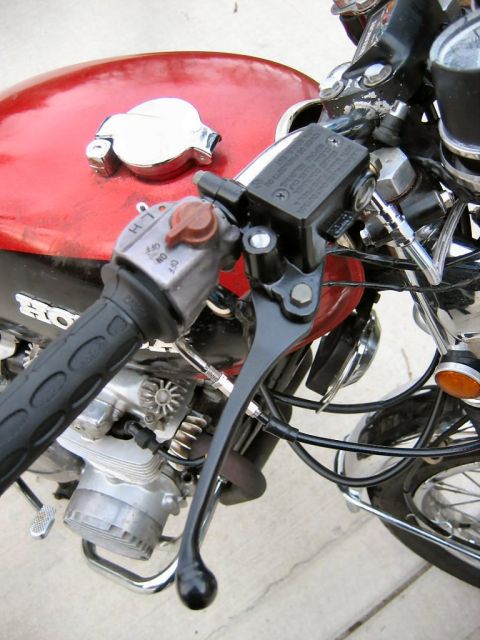 1985 Ford LTD Crown Victoria - Close-up view of a red motorcycle's gas tank, handlebars, and engine components.