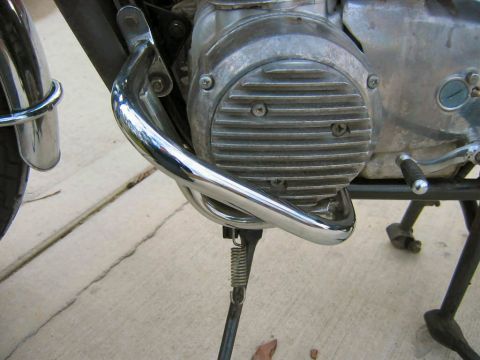 1985 Ford LTD Crown Victoria - A chrome crash bar is mounted to the frame of a motorcycle, near the engine block.
