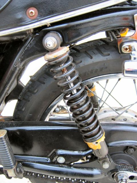1985 Ford LTD Crown Victoria - Close-up of a motorcycle's rear suspension system, showing the shock absorber and part of the tire.