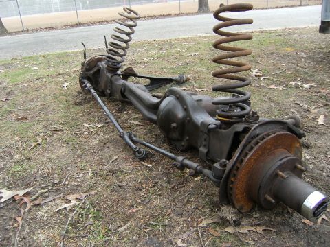 1992 Ford F-150 - A disassembled front axle assembly, including coil springs and brake components, lies on the ground.