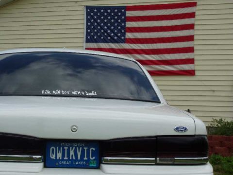 1996 Ford Crown Victoria - Rear view of a white 1996 Ford Crown Victoria, a Michigan license plate and an American flag on the wall.