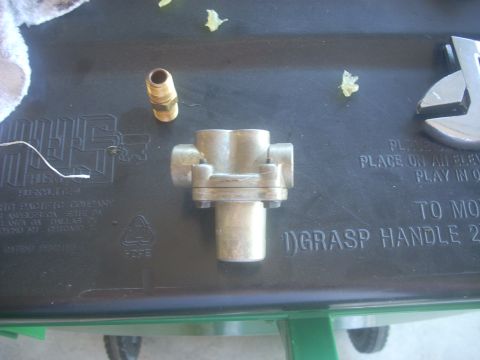 1992 Ford Bronco - Brass pneumatic fitting with multiple ports and a hose barb fitting are shown on a textured surface.