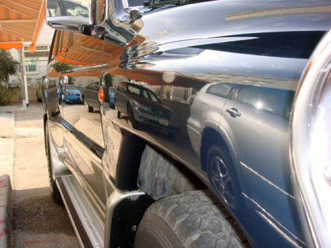 2000 Mitsubishi Montero - Reflection of a silver SUV is visible on the polished side of a dark SUV, with a Supermotors.net logo in the lower right corner.