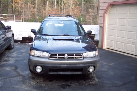 2001 Ford Crown Victoria - A Subaru Outback is parked in a driveway next to a garage with snow in the background.