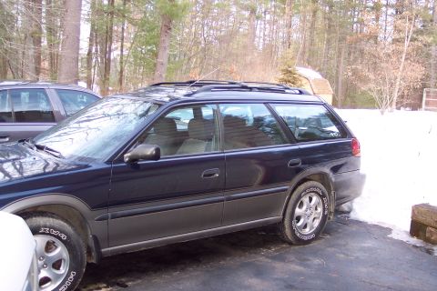 2001 Ford Crown Victoria - A dark blue Subaru Outback station wagon is parked on a driveway with snow on the ground.