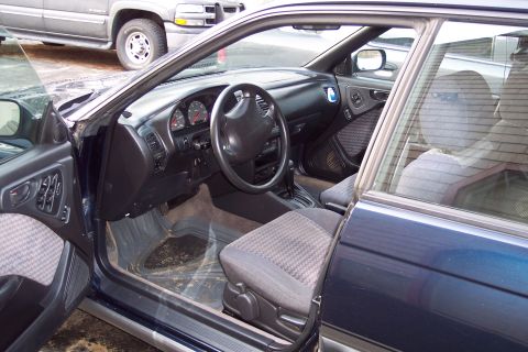 2001 Ford Crown Victoria - The interior of a dark blue car is visible, with a dashboard, steering wheel, and seats. Another vehicle is partially visible in the backgr…