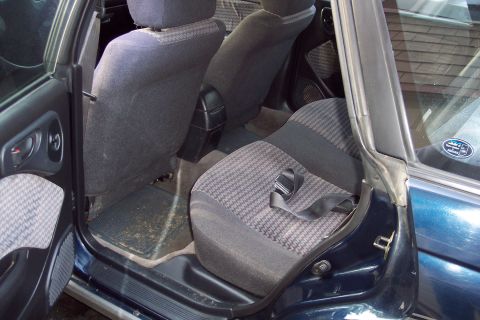 2001 Ford Crown Victoria - The interior of a dark blue car shows the rear seats and an open door, revealing a houndstooth fabric pattern.