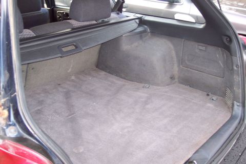 2001 Ford Crown Victoria - The cargo area of a station wagon is shown, a retractable cover and grey carpeting.