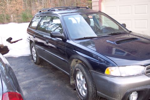 2001 Ford Crown Victoria - A dark blue Subaru Outback wagon is parked in a driveway with snow visible on the ground.