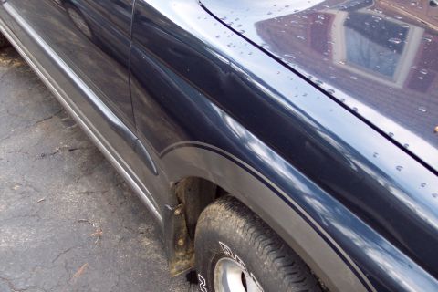 2001 Ford Crown Victoria - Side view of a dark blue SUV, showing its fender and tire with silver pinstriping detail.