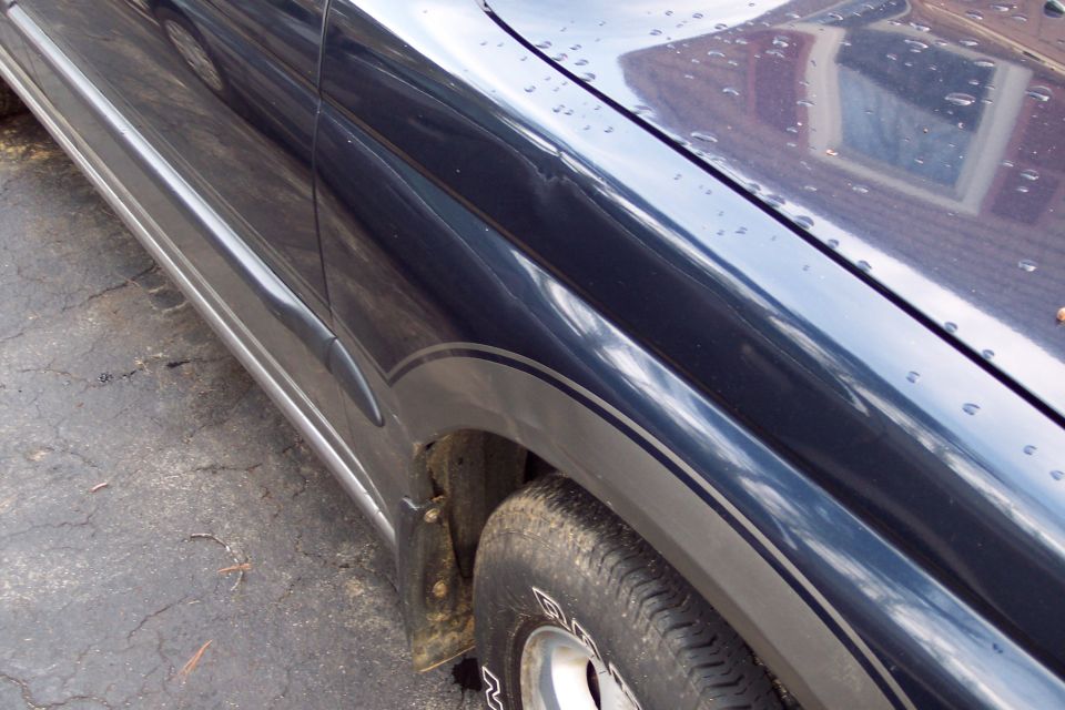 Dark blue SUV fender and side panel with silver pinstriping, tire visible