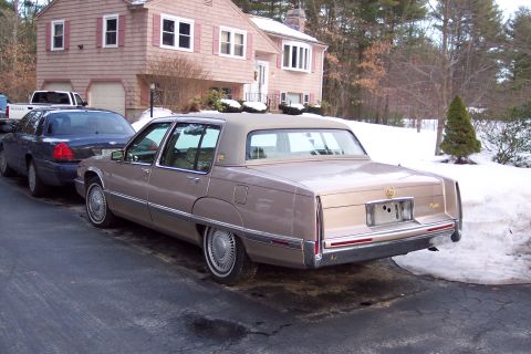 2001 Ford Crown Victoria - Two sedans are parked in a driveway during winter, with a house in the background.