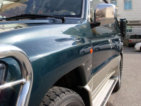 2000 Mitsubishi Montero - Front quarter view of a green Mitsubishi Montero showing the fender, bull bar, and side steps.