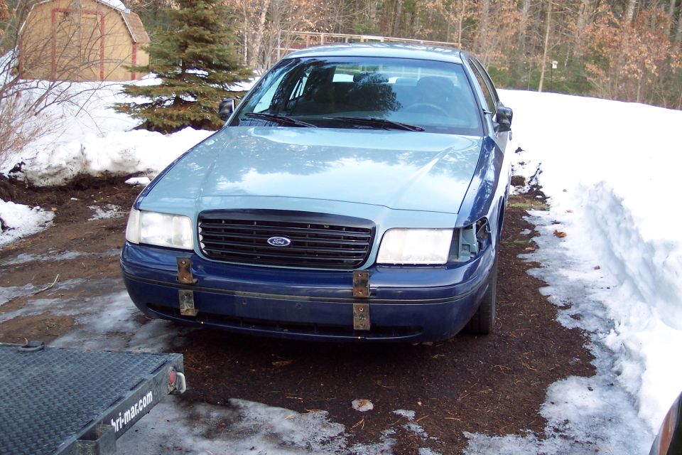 Front view of a blue and light blue 2001 Ford Crown Victoria parked in a snowy area