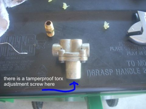 1992 Ford Bronco - A metal valve assembly and a brass fitting are shown on a black surface with a wrench.