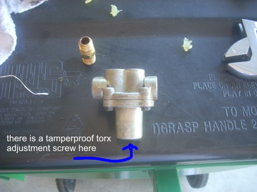 Metal valve assembly with brass fitting on black surface, wrench visible
