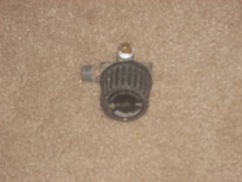 1992 Ford Bronco - A black air filter with a ribbed casing and a brass fitting is shown against a carpeted background.