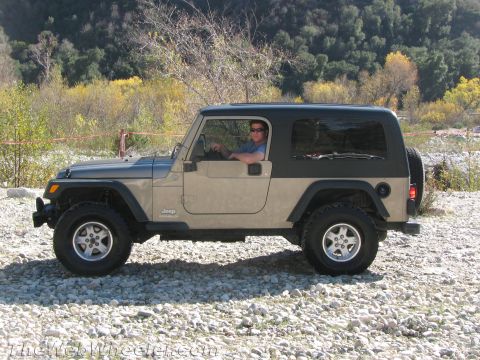 1987 Suzuki Samurai - A Jeep Wrangler is parked on a rocky area with trees in the background.