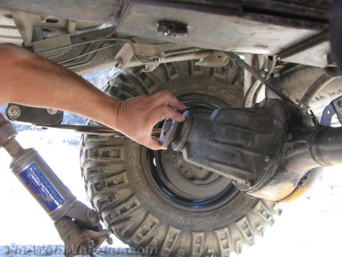 1987 Suzuki Samurai - Close-up view of a vehicle's rear axle and wheel assembly, with a hand interacting with the hub.