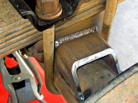 1996 Ford Bronco - Close-up of a welded bracket attached to a vehicle's leaf spring suspension system, showing U-bolts and a clamp.