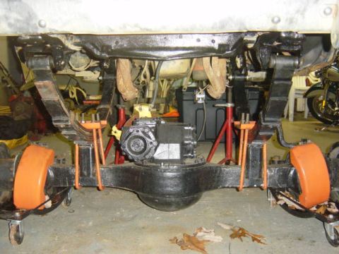 1987 Suzuki Samurai - The rear suspension and drivetrain components of a vehicle are visible, raised on jack stands for maintenance.