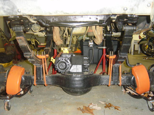 Undercarriage view of a vehicle's rear axle, leaf springs, and differential, supported by jack stands