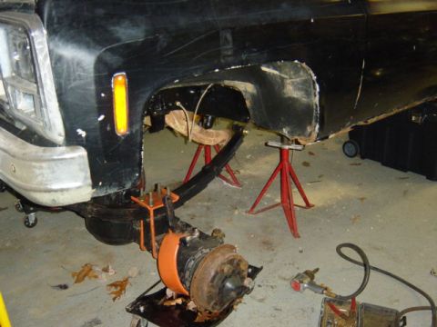 1987 Suzuki Samurai - Front section of a black truck undergoing repairs, with the suspension system disassembled.