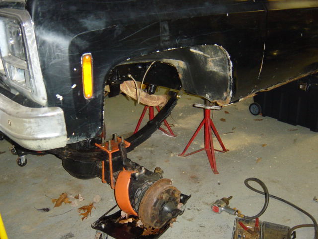 Black truck front fender and chassis on jack stands, with suspension removed