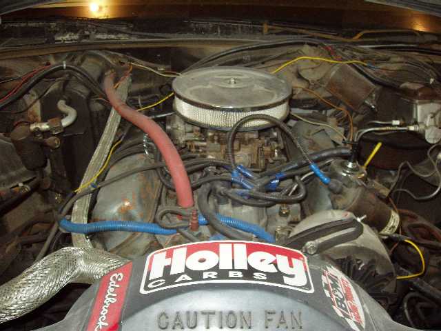 engine bay with Holley carburetor and air cleaner, some wiring and hoses visible