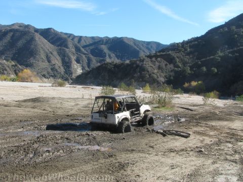1987 Suzuki Samurai - Suzuki Samurai deep in mud, with mountains visible behind it.