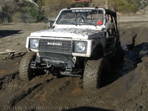 1987 Suzuki Samurai - This 1987 Suzuki Samurai is deep in the mud, showing its off-road capabilities and modifications.